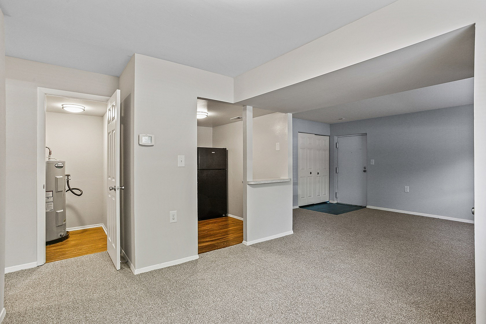 Inviting apartment interior with plush carpeting and sleek kitchen area, showcasing modern open-concept design and ample natural light.