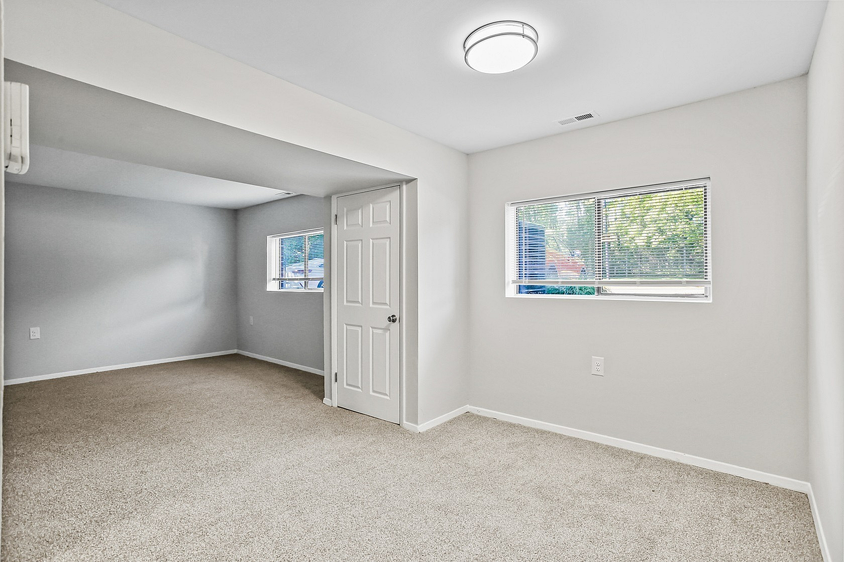 Bright and inviting empty room with plush carpet and large windows, perfect for customization in a modern apartment.