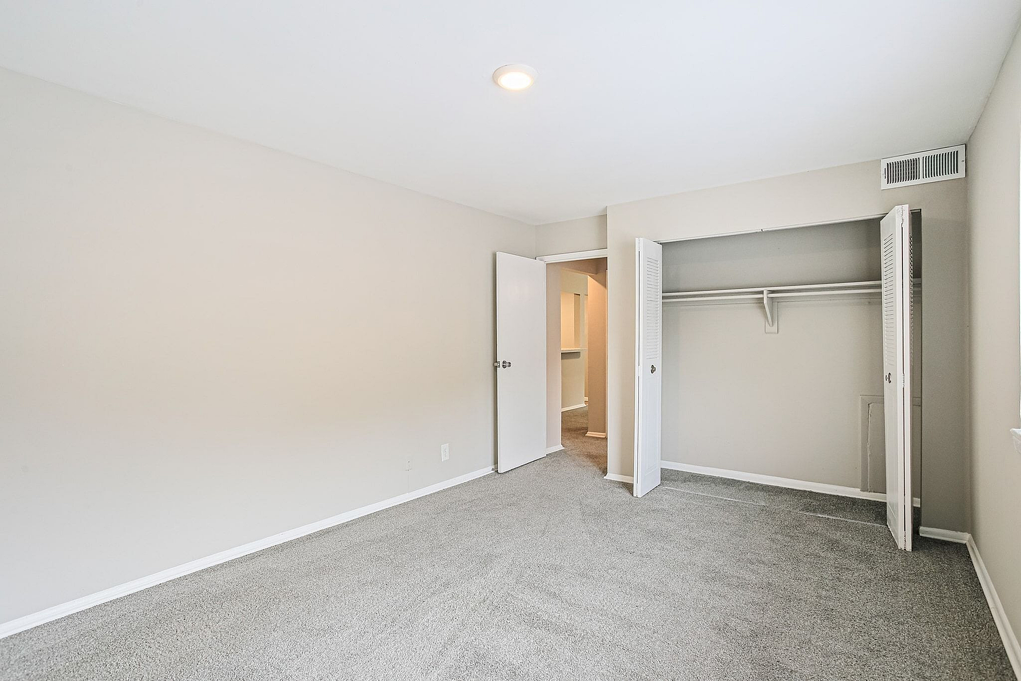 Spacious bedroom with plush carpet, ample closet space, and soft natural lighting creating a cozy ambiance.