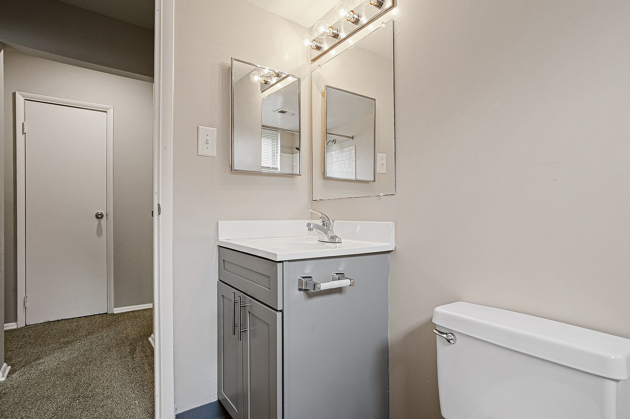 Chic apartment bathroom featuring modern vanity with sleek mirrors and elegant lighting.