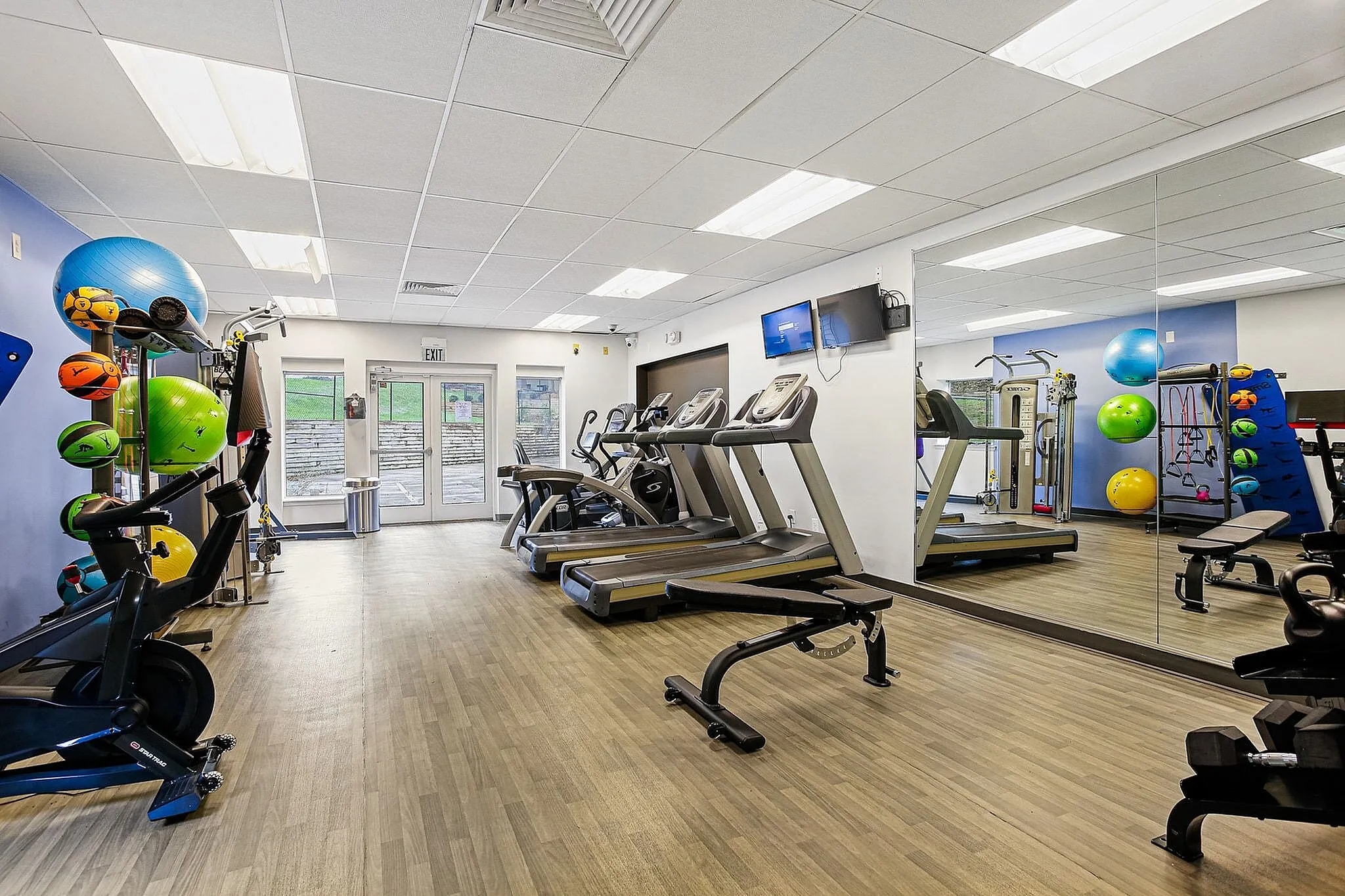 Modern fitness center with state-of-the-art treadmills, colorful exercise balls, and sleek design elements.