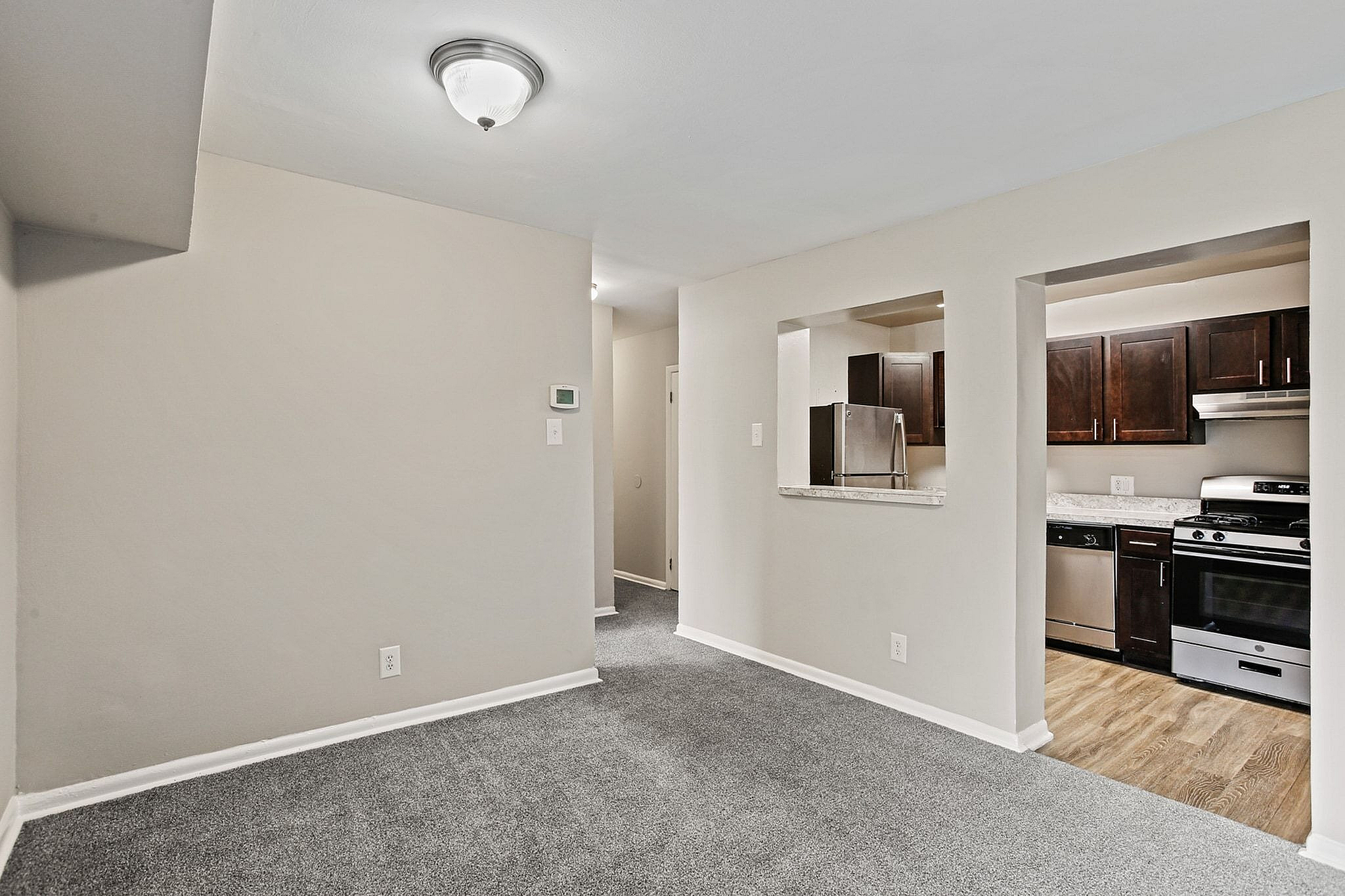 Modern apartment interior showcasing an open-concept layout with stylish dark wood kitchen cabinets and elegant stainless steel appliances.