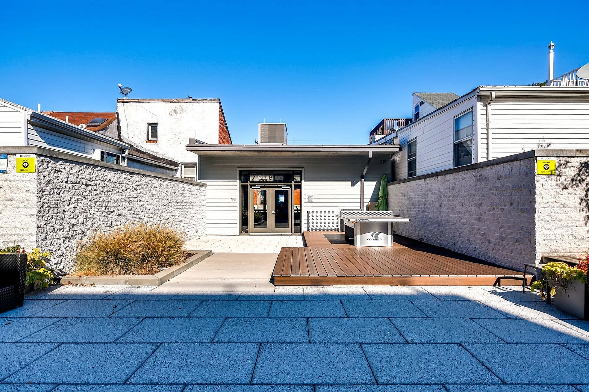 Chic outdoor patio featuring modern stone flooring, inviting lounge area, and vibrant landscaping under a clear blue sky.