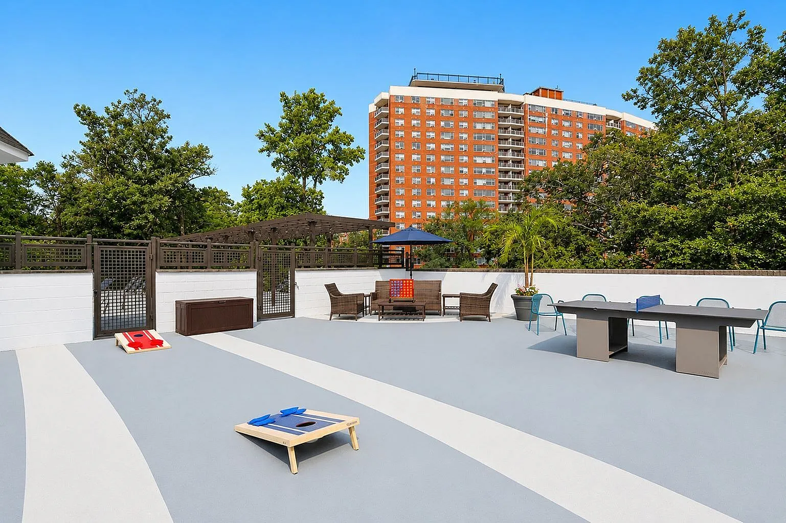 Vibrant apartment community terrace with stylish seating, games, and lush greenery under a clear blue sky.