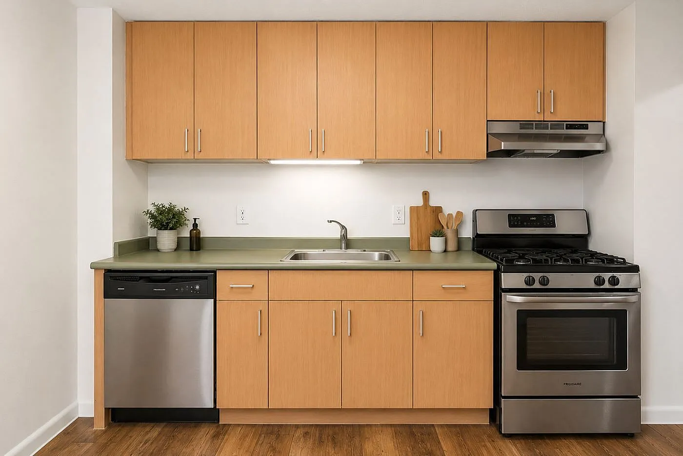 Contemporary kitchen with sleek stainless steel appliances, natural wood cabinets, and a chic green countertop, offering a modern cooking space.