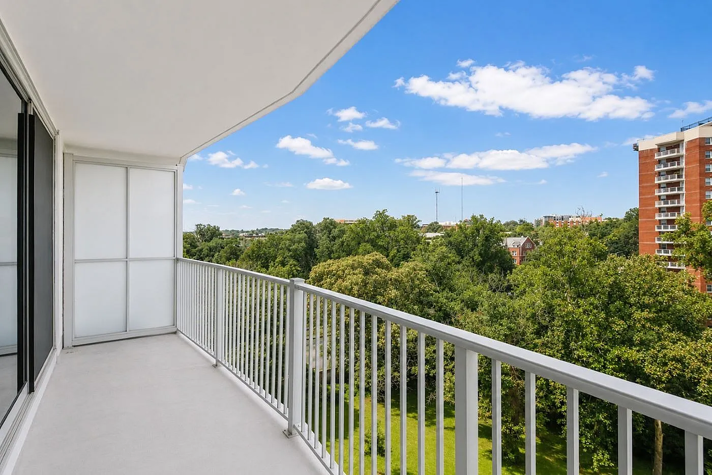 Luxurious balcony with stunning panoramic views of lush greenery and clear blue skies.