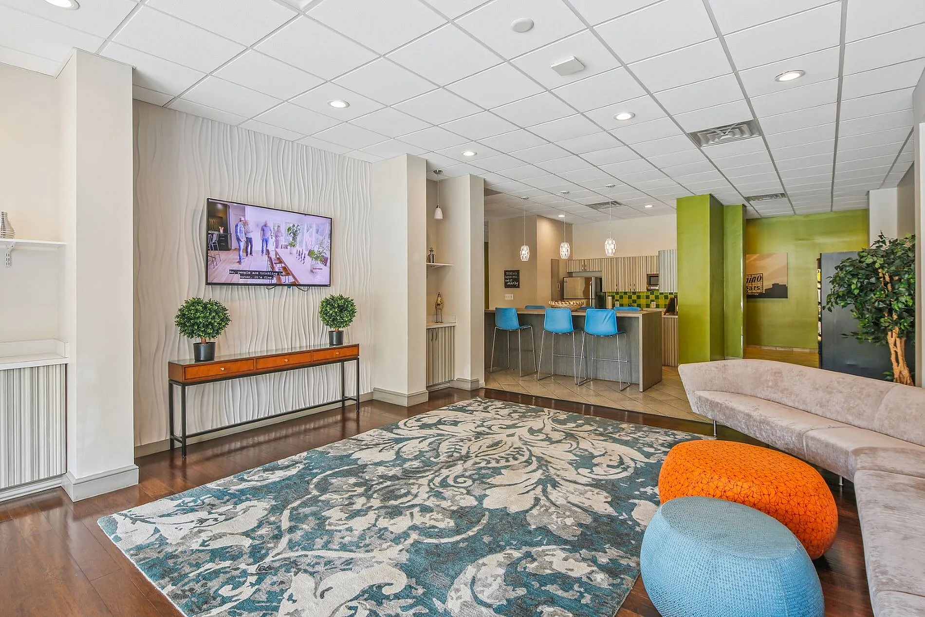 Modern lounge area featuring stylish decor with a patterned rug, elegant seating, and a vibrant bar with blue stools.