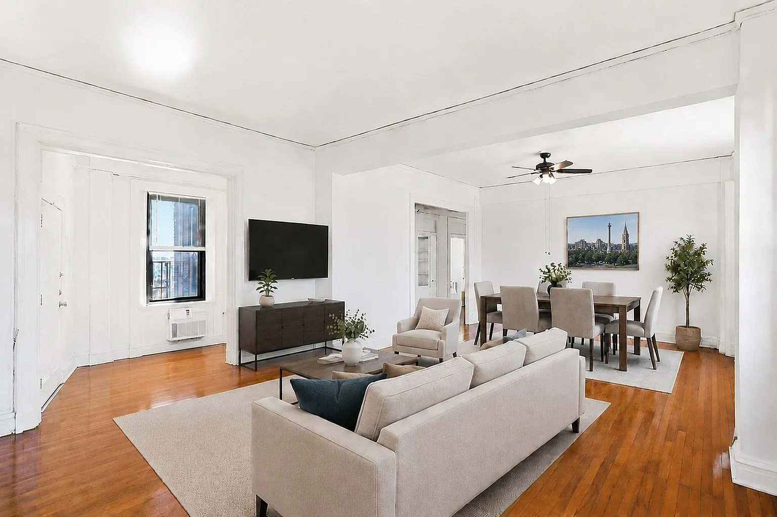 Bright and elegant open-plan living and dining area featuring polished hardwood floors, modern furniture, and a wall-mounted TV for a cozy atmosphere.