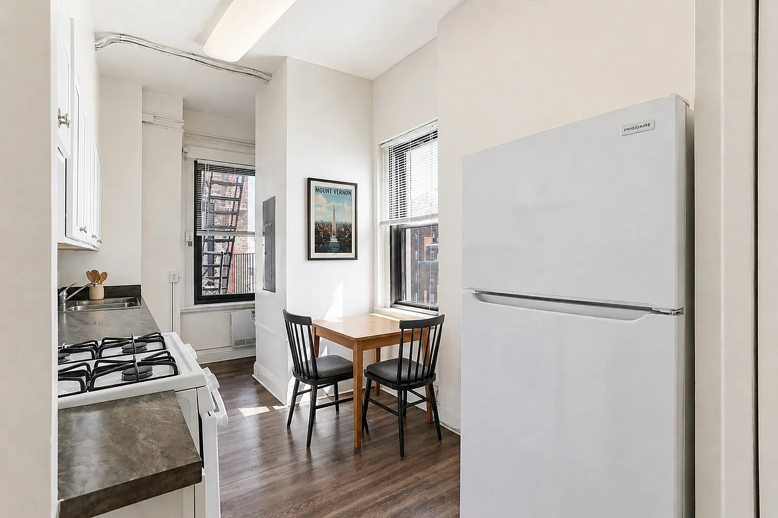 Bright and inviting kitchen with modern appliances, wood flooring, and a cozy breakfast nook perfect for intimate meals.