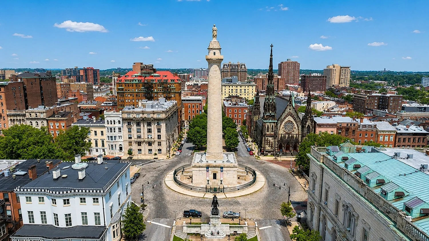 Breathtaking aerial view of historic city square featuring a majestic monument, surrounded by charming architecture and lush greenery.