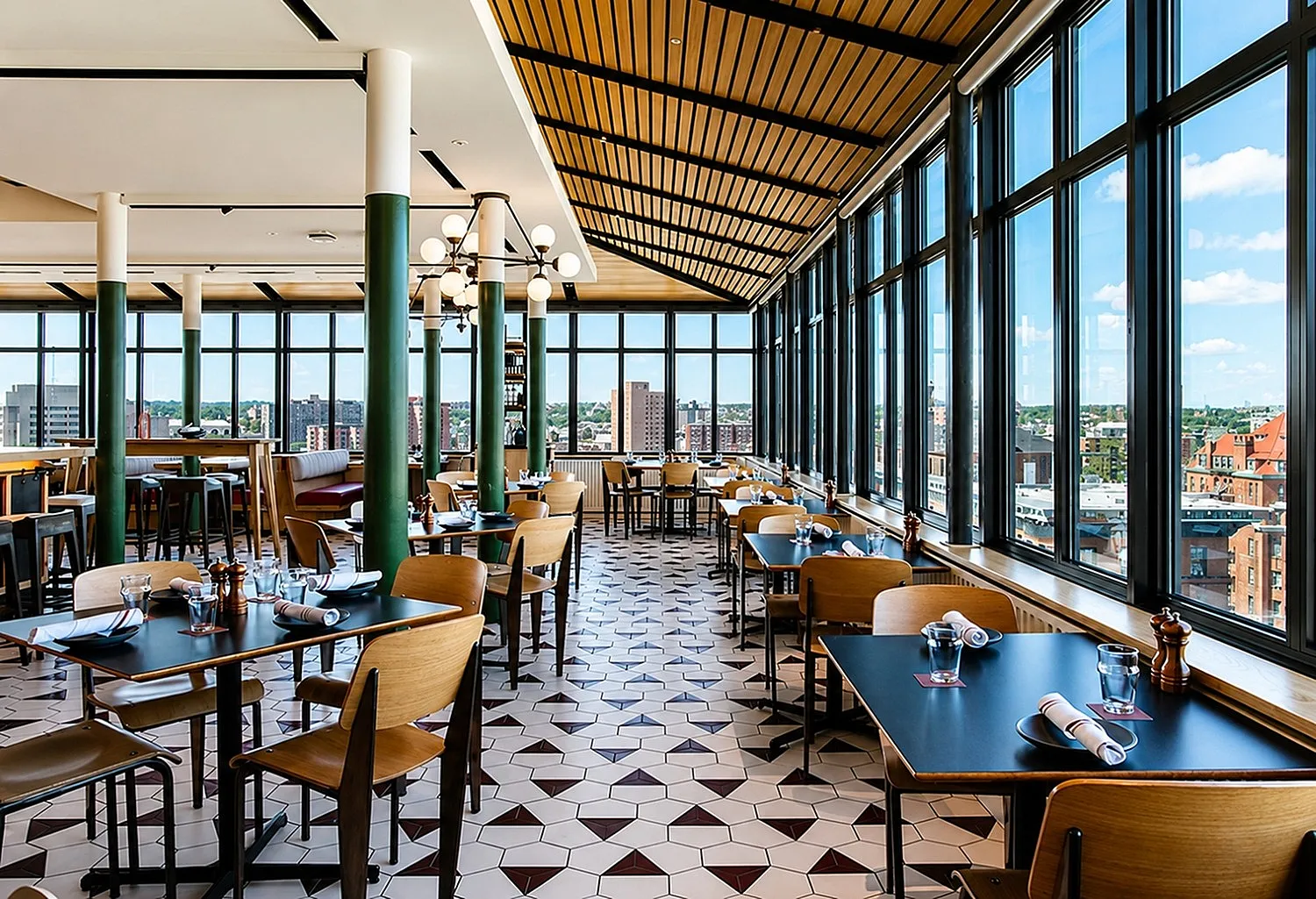 Vibrant restaurant with large panoramic windows offering stunning city views, featuring stylish decor and modern dining ambiance.