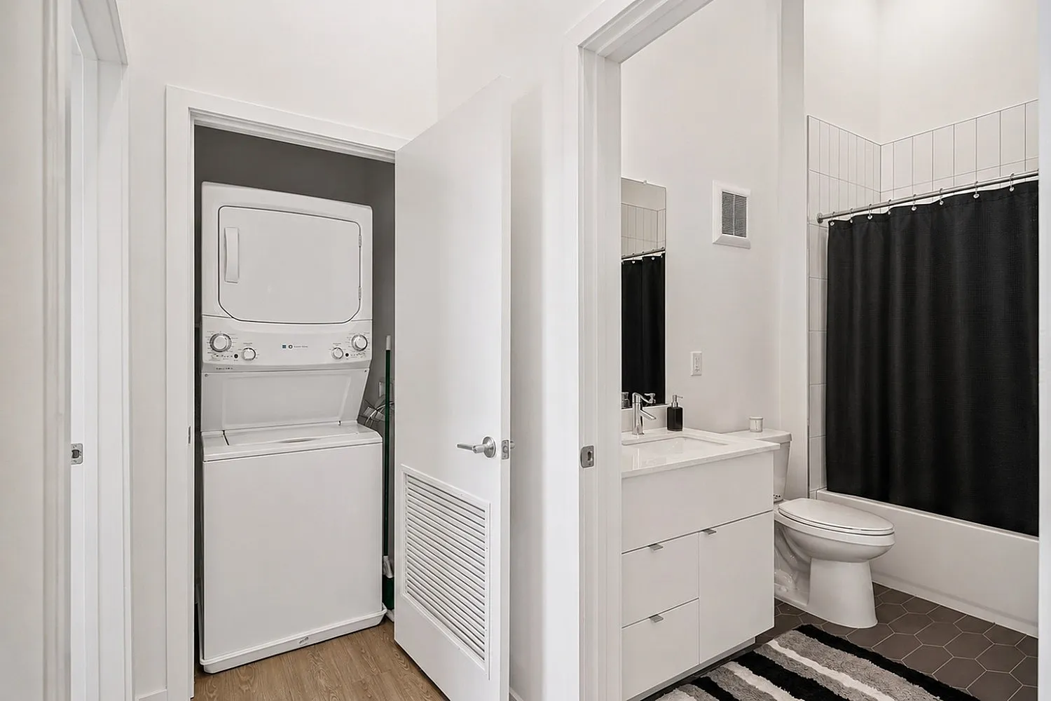 Modern apartment bathroom with sleek vanity, bright lighting, and in-unit stacked washer and dryer for convenience.