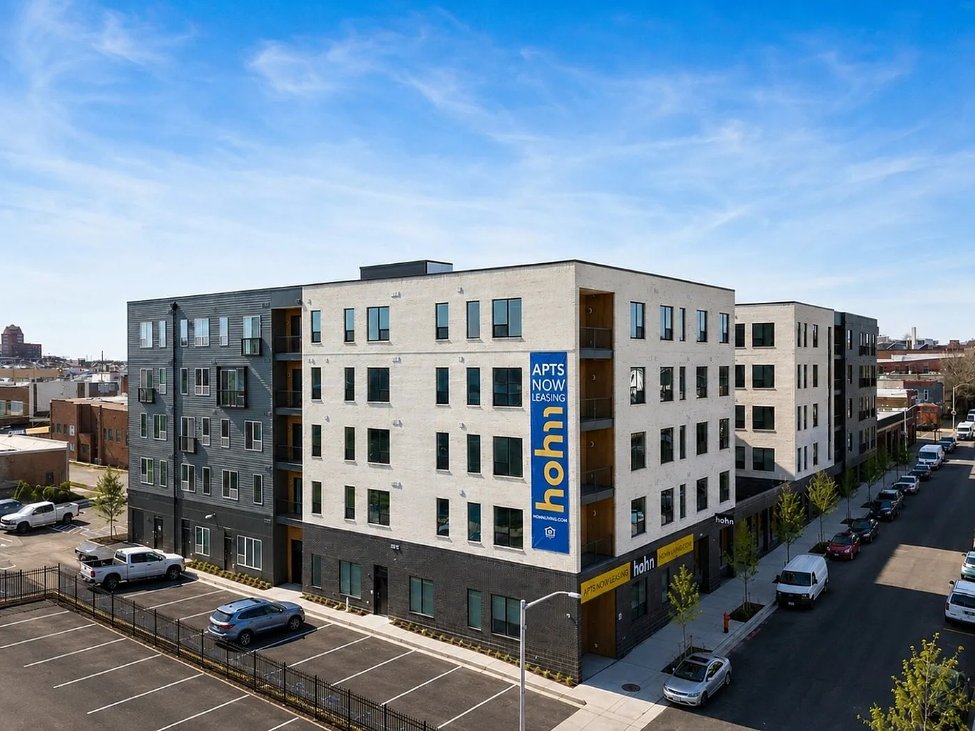 Contemporary apartment complex with modern architecture, showcasing ample parking and vibrant urban surroundings.