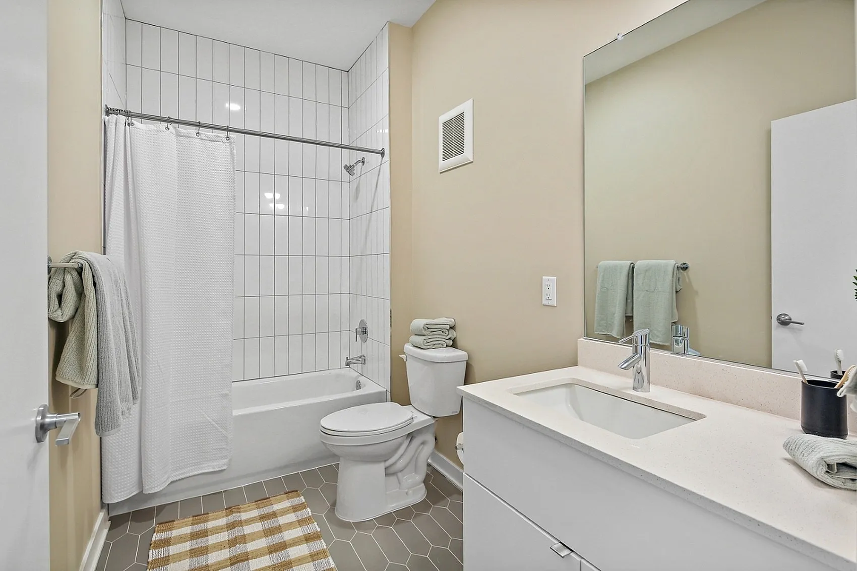 Modern bathroom with sleek white tiles, elegant vanity, and relaxing bathtub in a pristine apartment.