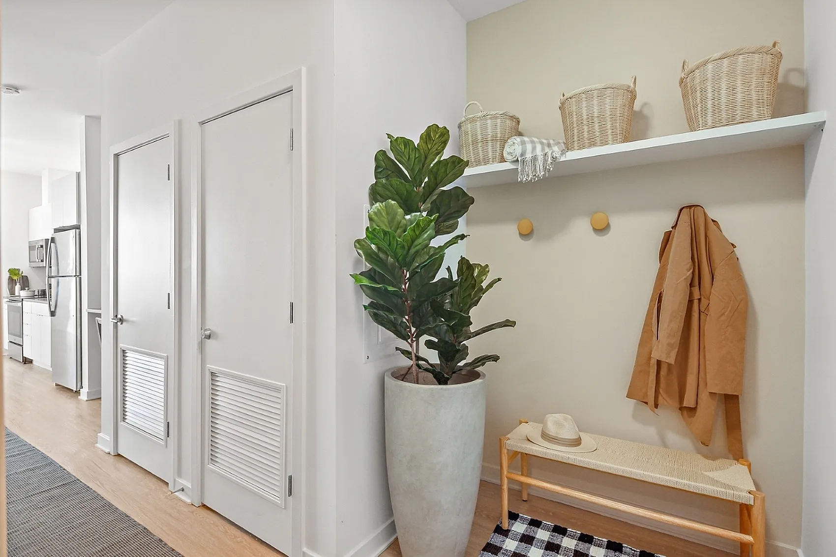 Modern apartment hallway featuring sleek white doors, lush potted plant, and organized shelf with baskets for stylish storage.