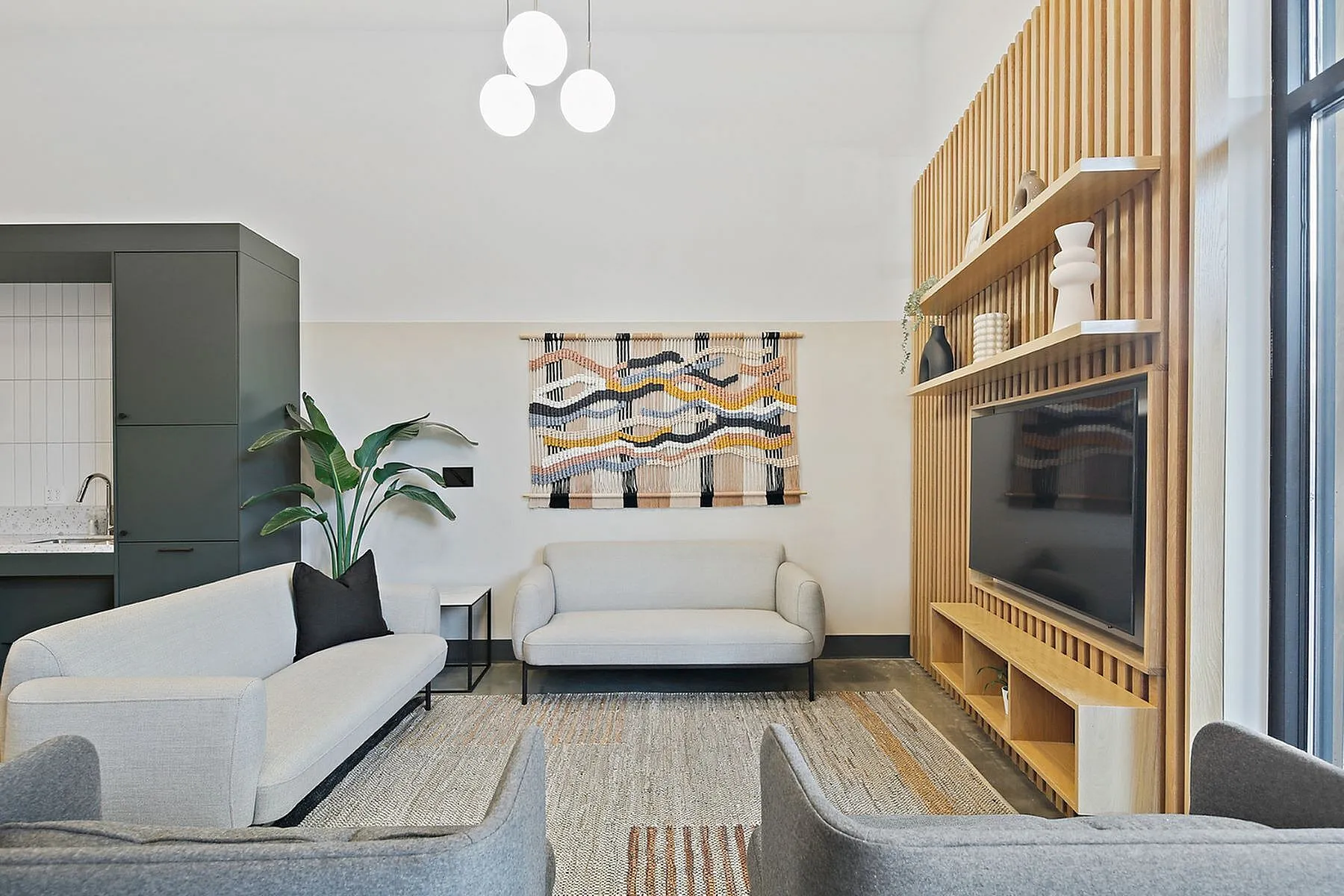 Chic living room with modern gray sofas, stylish wooden wall paneling, and vibrant art piece, offering a cozy and contemporary ambiance.