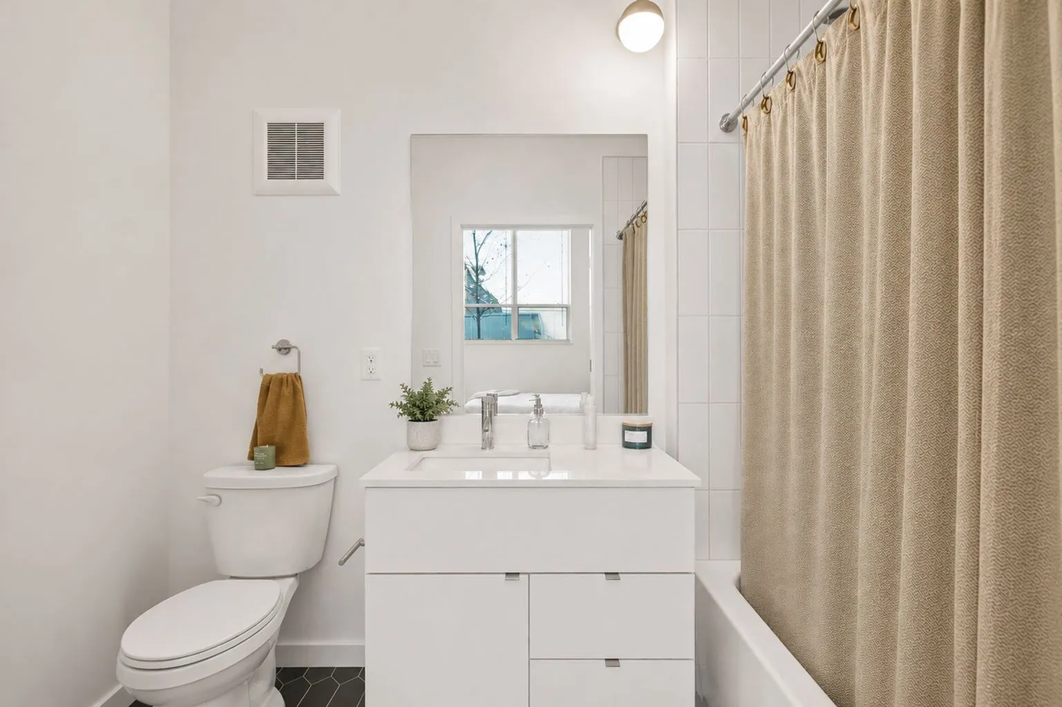 Bright and modern bathroom featuring a sleek white vanity, elegant tile flooring, and a spacious bathtub with a chic curtain.
