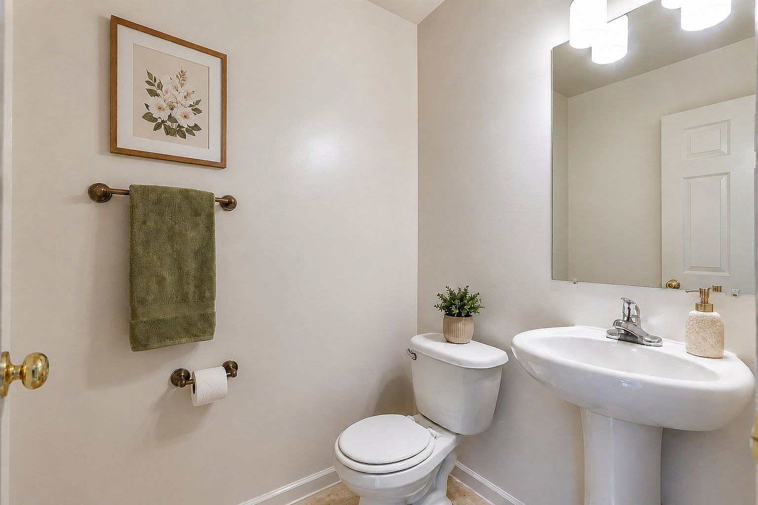 Charming, well-lit bathroom featuring a sleek pedestal sink, elegant wall art, and modern fixtures.