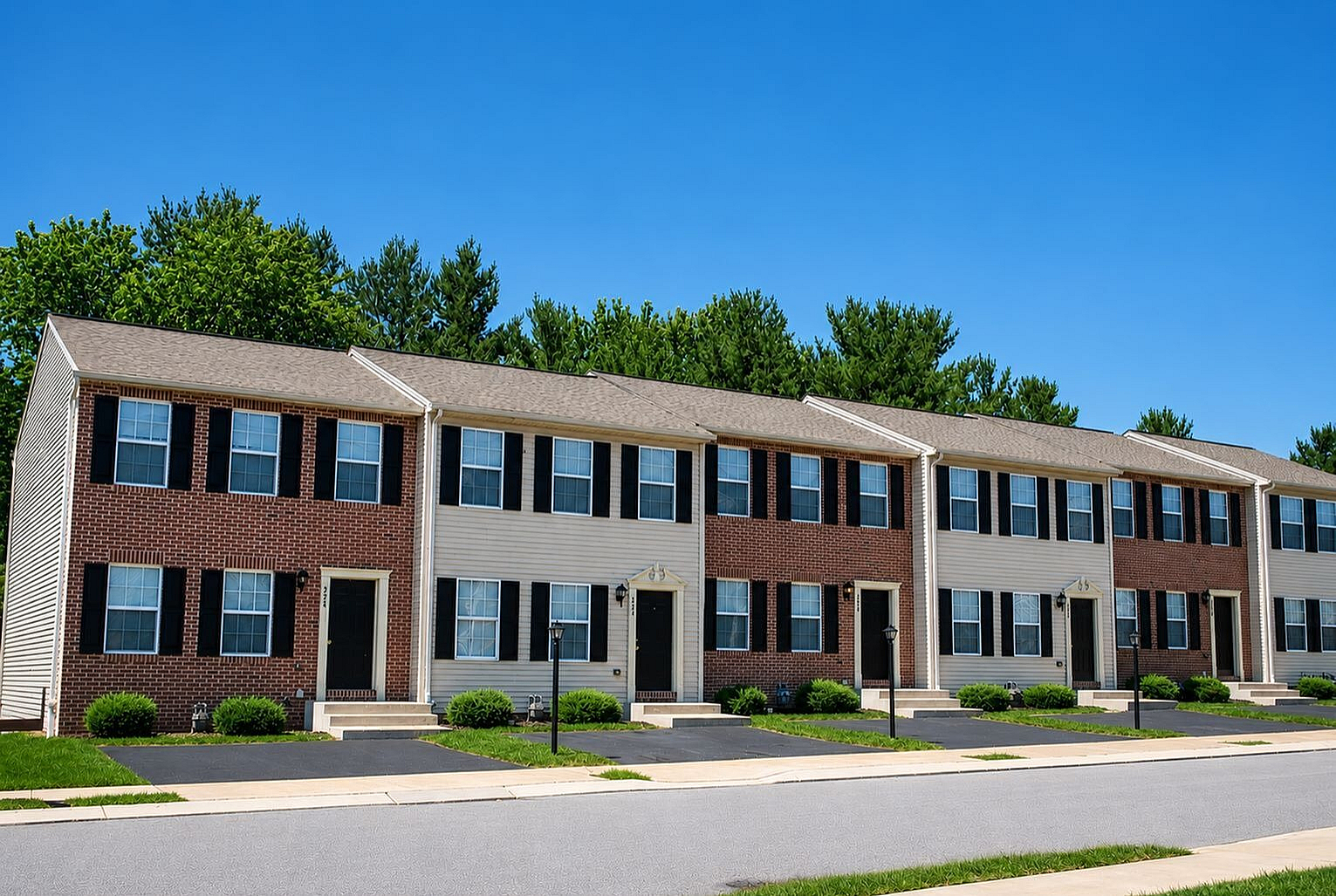 Charming row of modern townhouses with brick facades, nestled in a serene neighborhood with lush greenery.