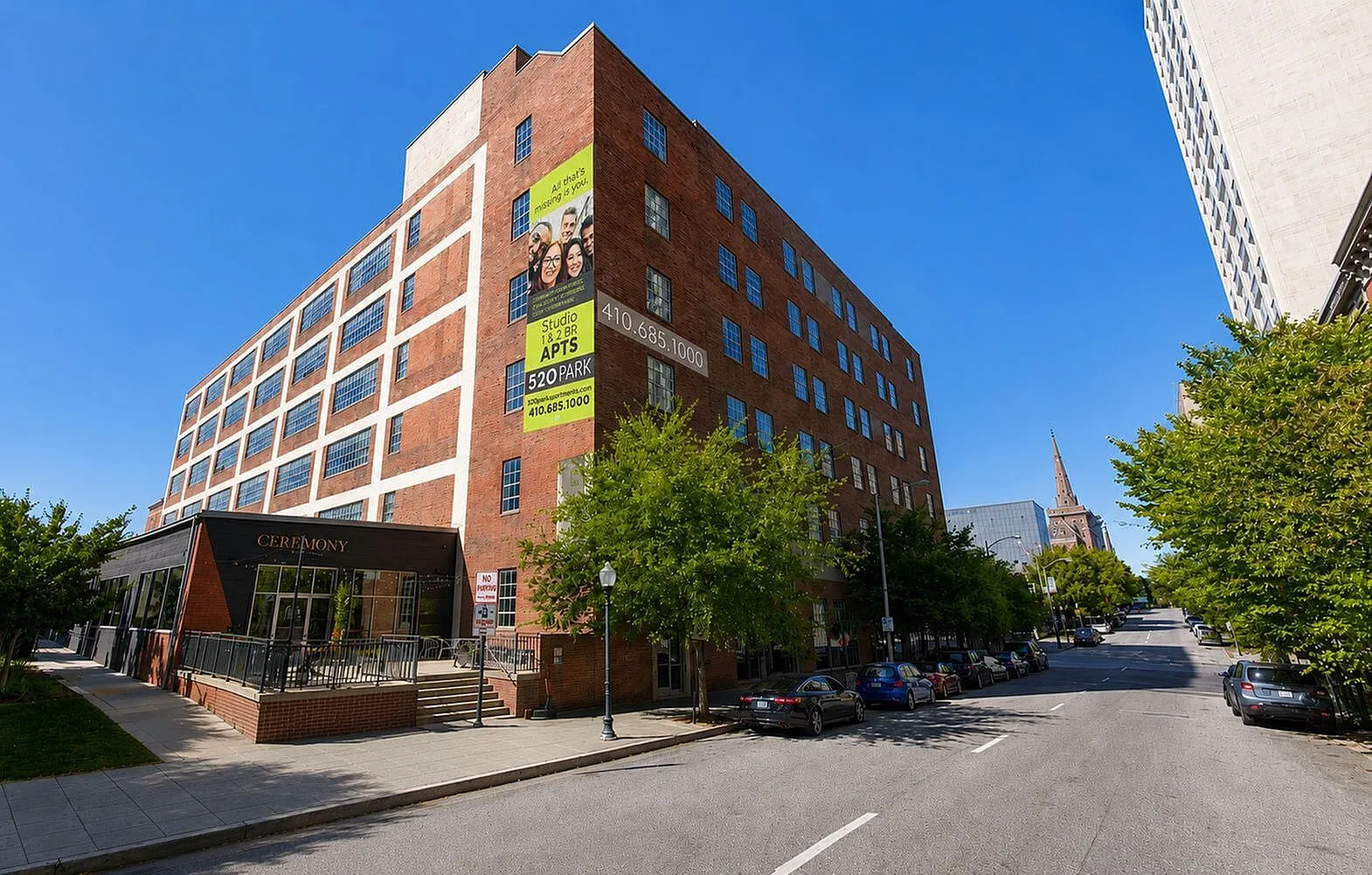 Modern red-brick apartment building featuring spacious studio and 1-2 bedroom apartments, conveniently located within a vibrant urban neighborhood.