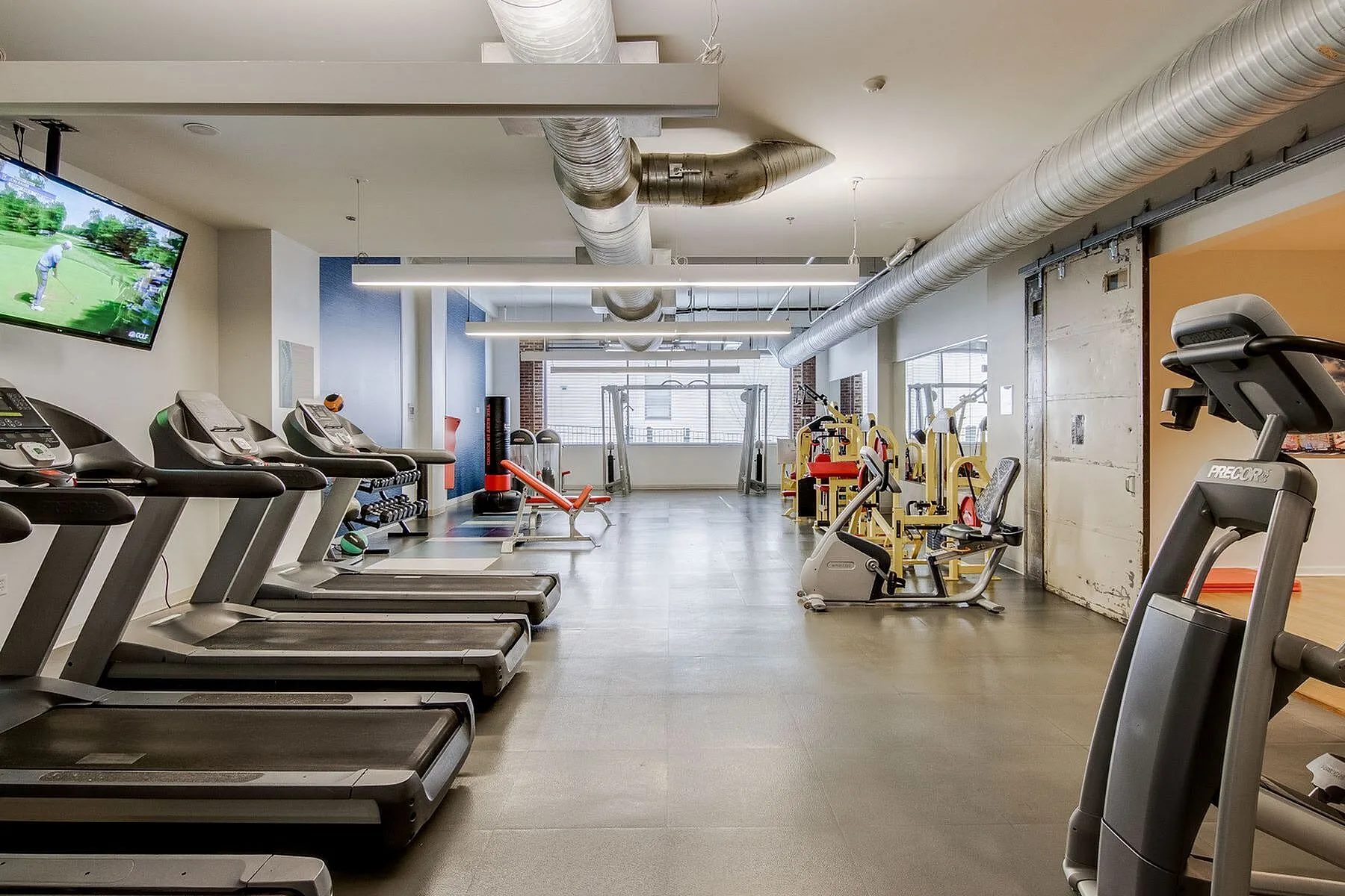 Spacious, modern fitness center featuring top-of-the-line treadmills, exercise machines, and flat-screen TV for an unparalleled workout experience.