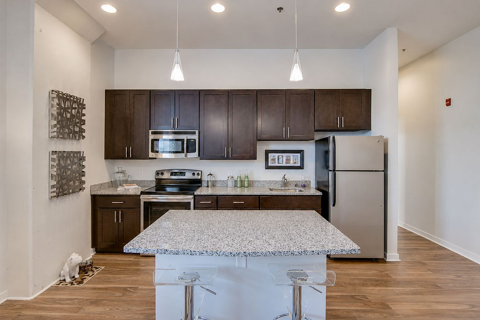 Modern kitchen with sleek dark wood cabinets, stainless steel appliances, and a stylish granite-topped island with chic pendant lighting.