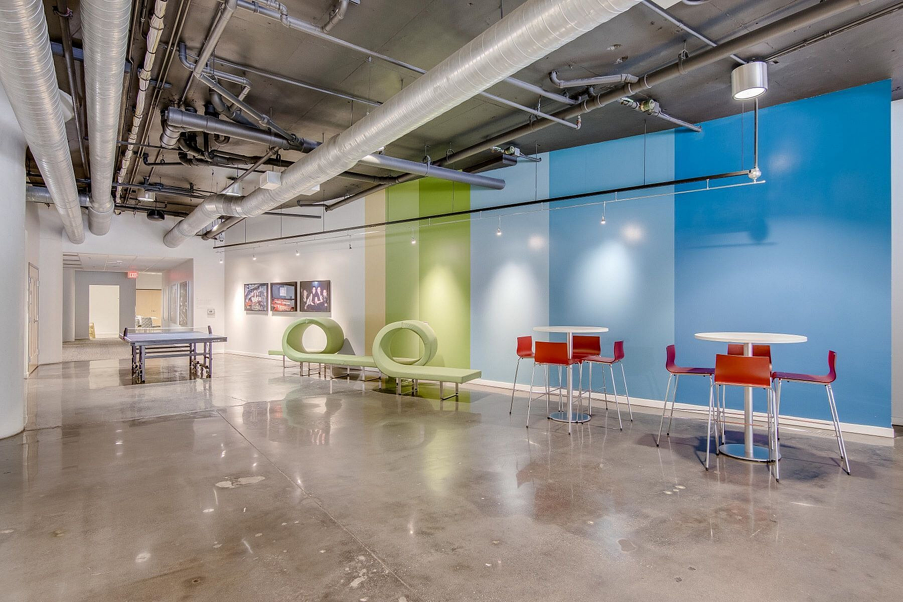 Modern industrial lounge with vibrant seating, colorful accent walls, and sleek concrete flooring.