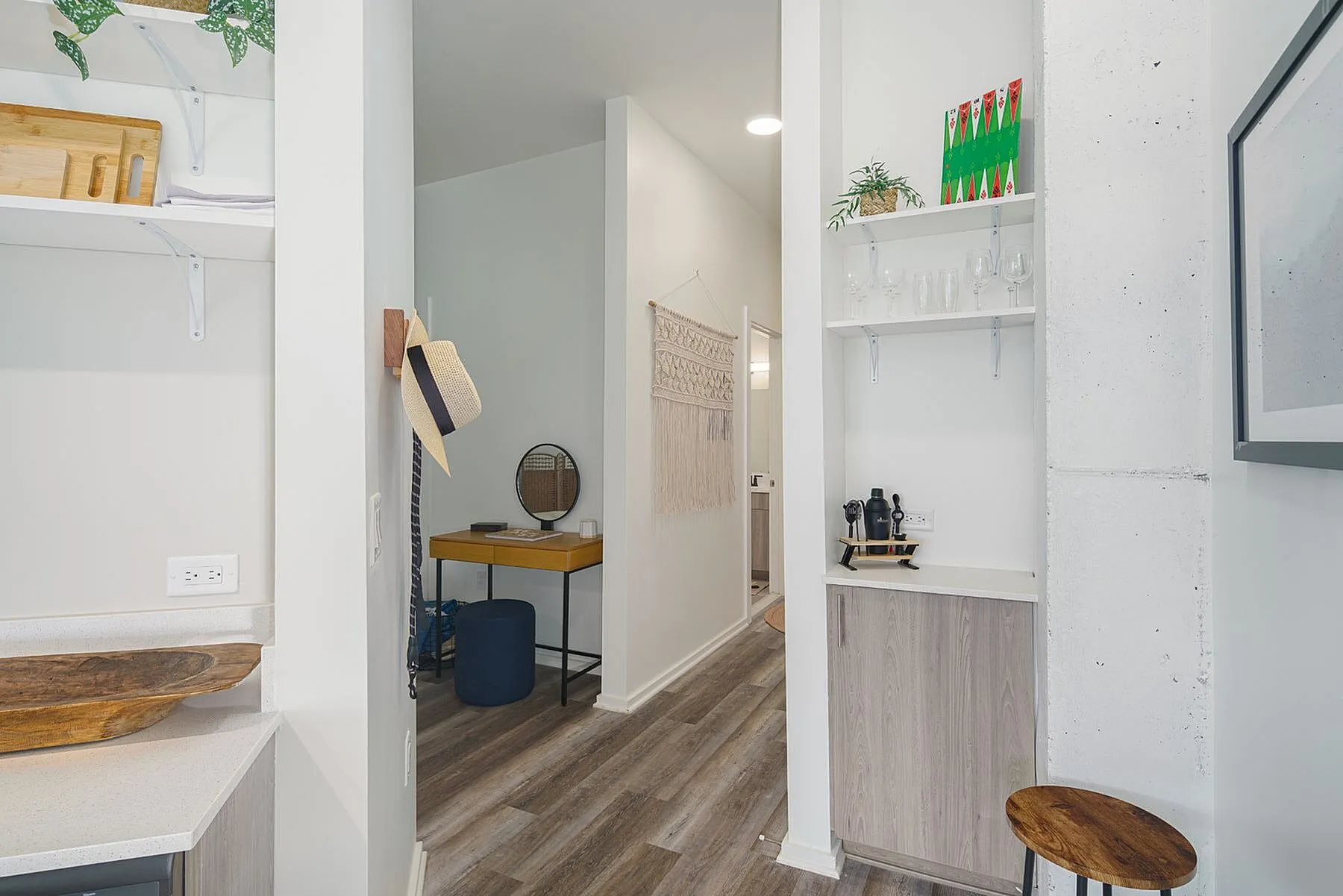 Charming entryway featuring sleek wood flooring, a cozy workspace with contemporary decor, and stylish wooden shelving.