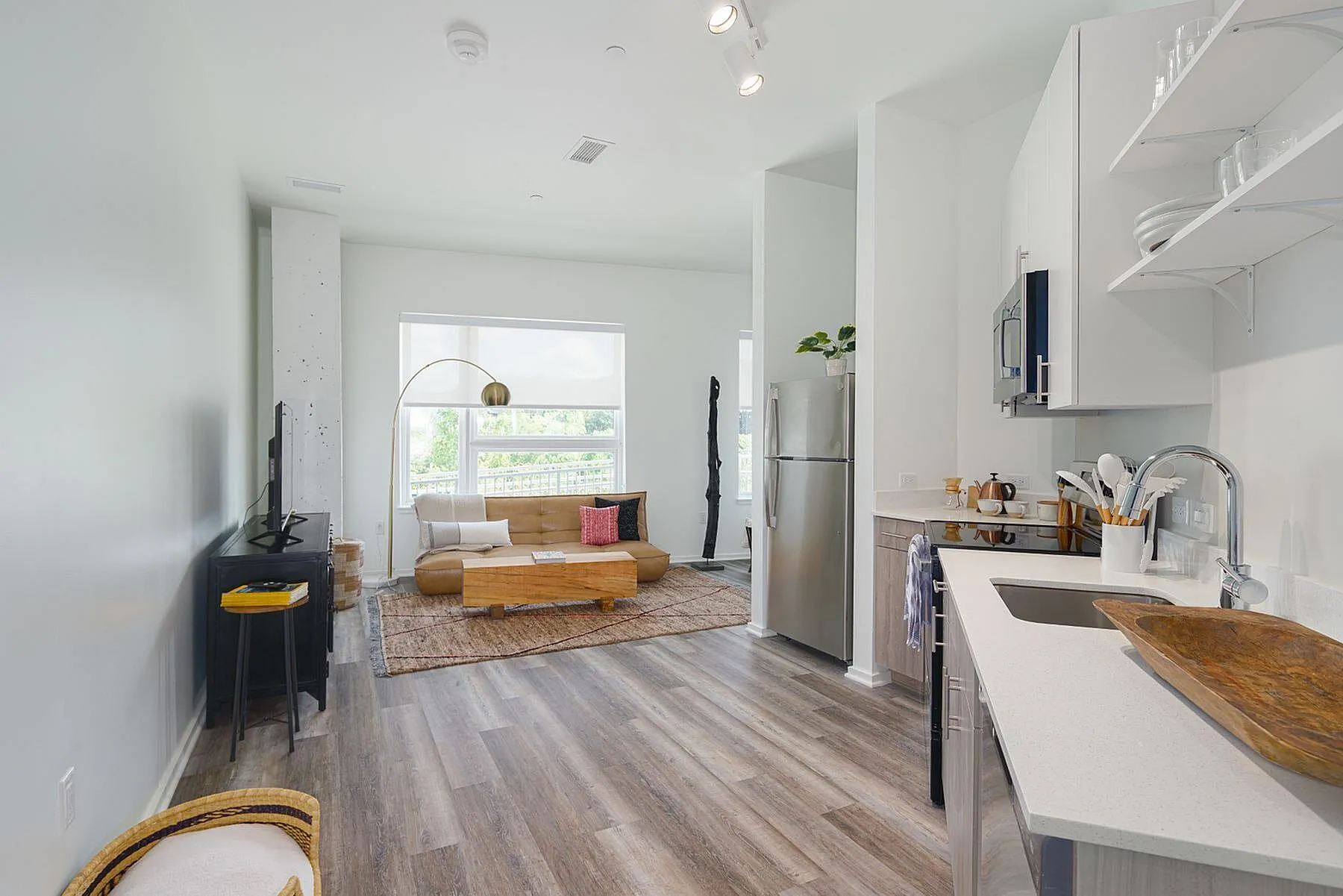 Bright and airy open-concept living space featuring modern kitchen, cozy seating area with stylish decor, and large window offering scenic views.