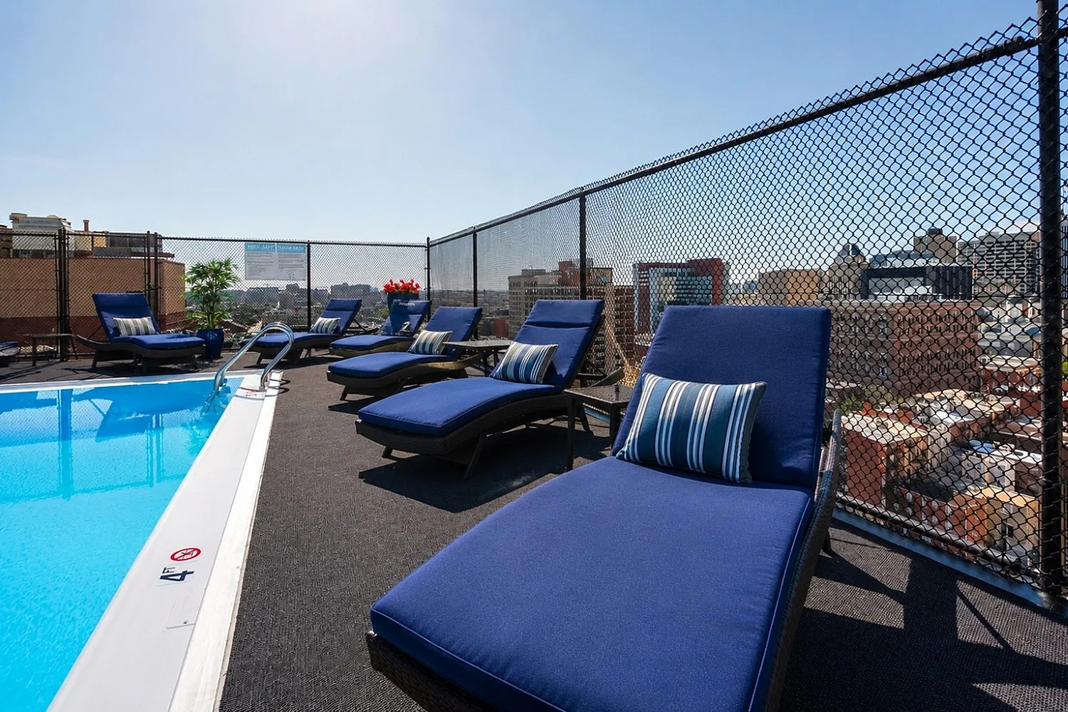 Luxurious rooftop pool with stylish blue loungers offering stunning city views.