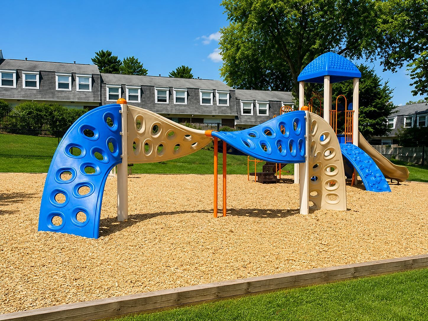 Vibrant playground with colorful climbing structures and slide, set against a backdrop of modern townhouses, offering family-friendly living.