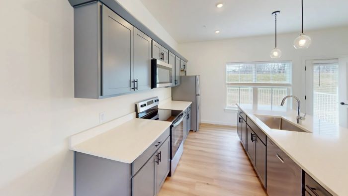 Emerson Flats modern kitchen with stainless steel appliances, gray cabinets, and quartz counter tops.