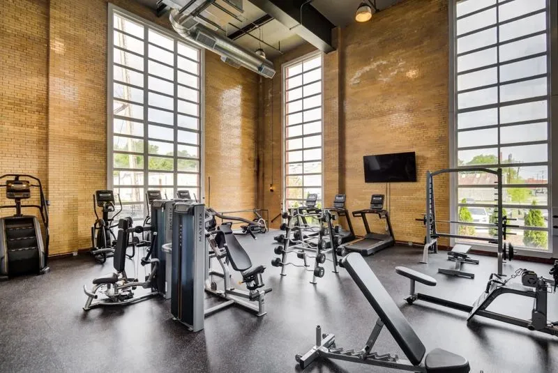 Spacious fitness center at Model Tobacco Apartments, showcasing a large window and a range of gym equipment.