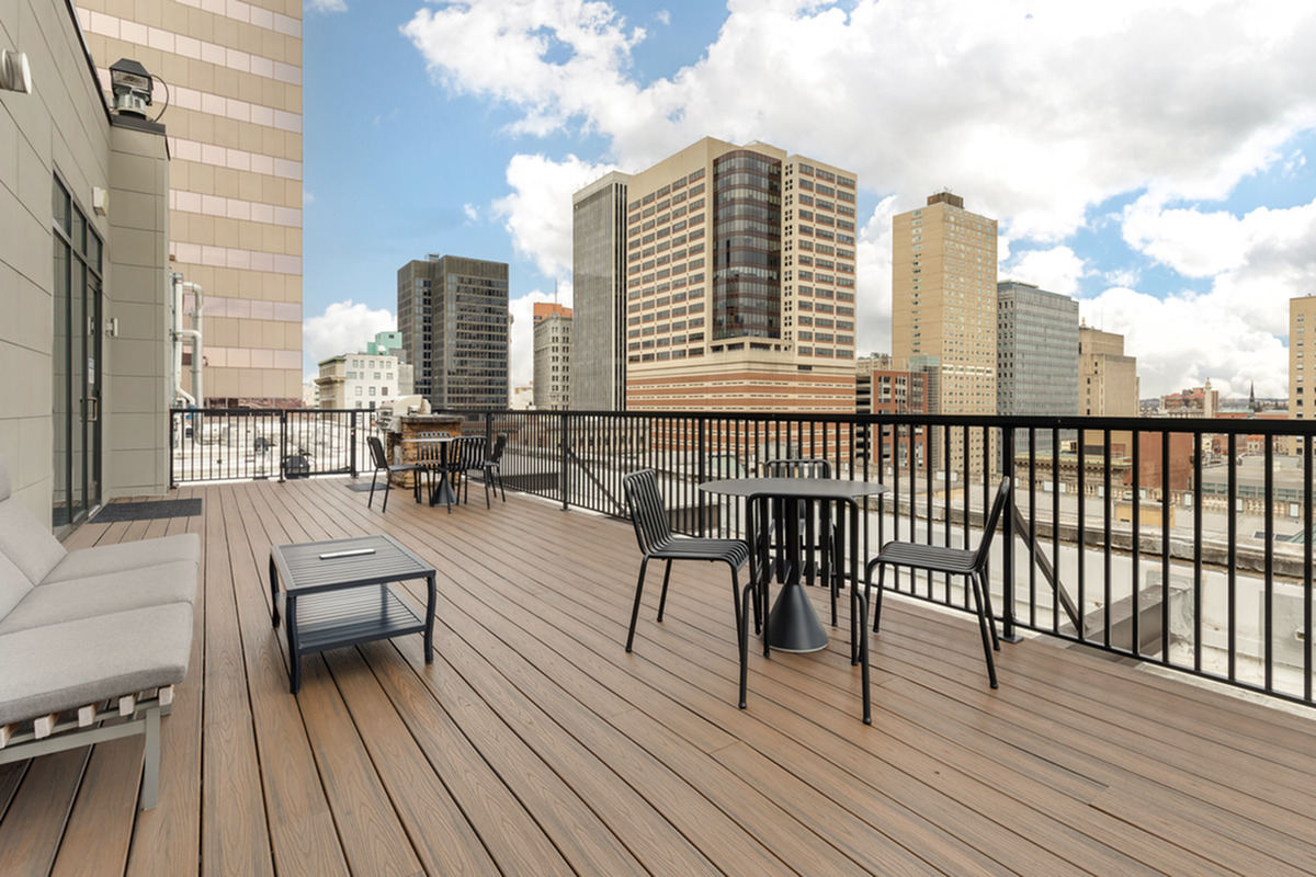 Spacious urban terrace with modern seating and skyline view under a bright blue sky.