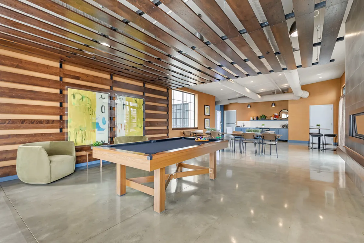 Contemporary lounge area with a pool table, stylish seating, and open kitchen.