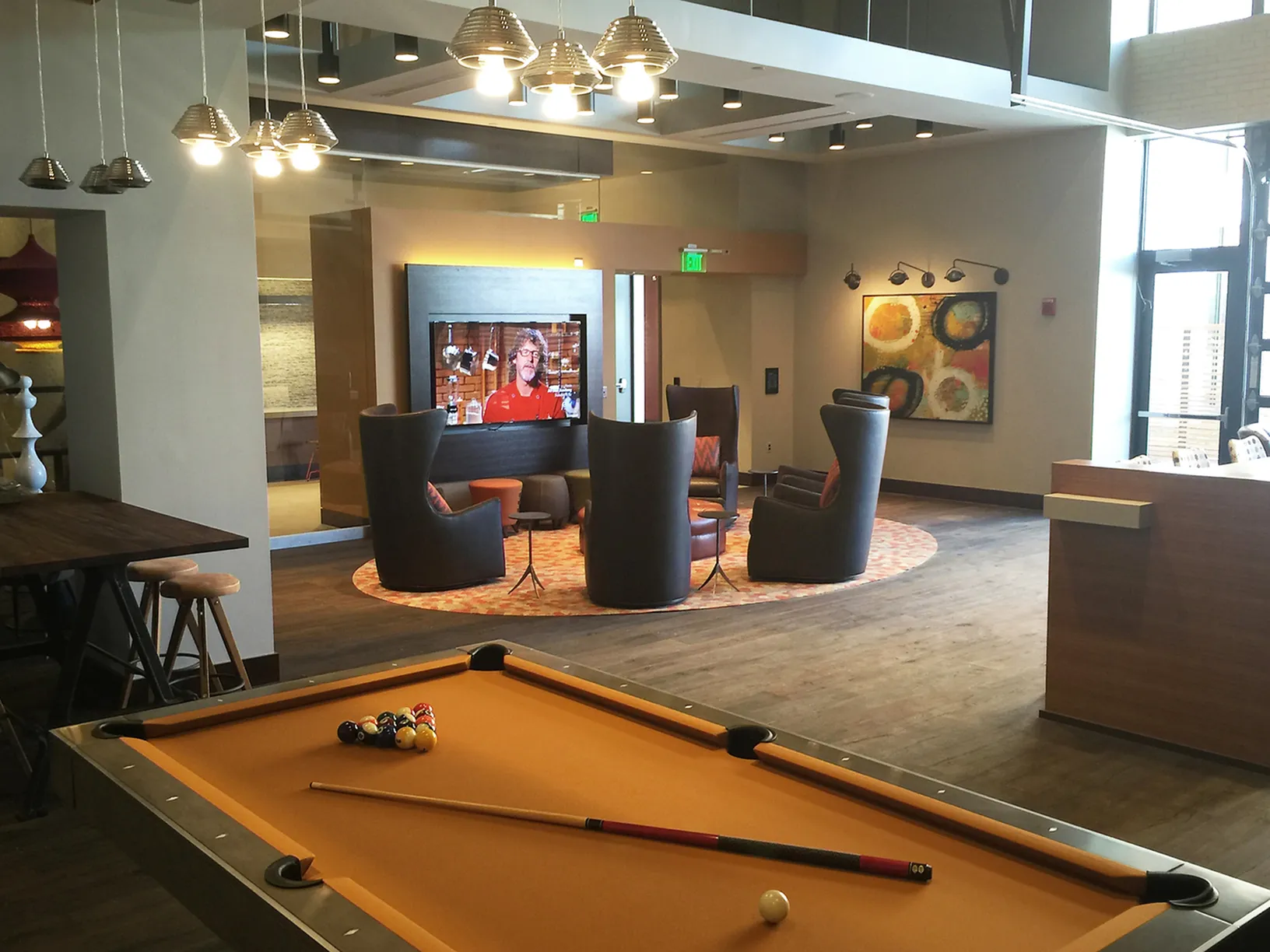 Modern lounge with pool table and stylish seating around a large TV