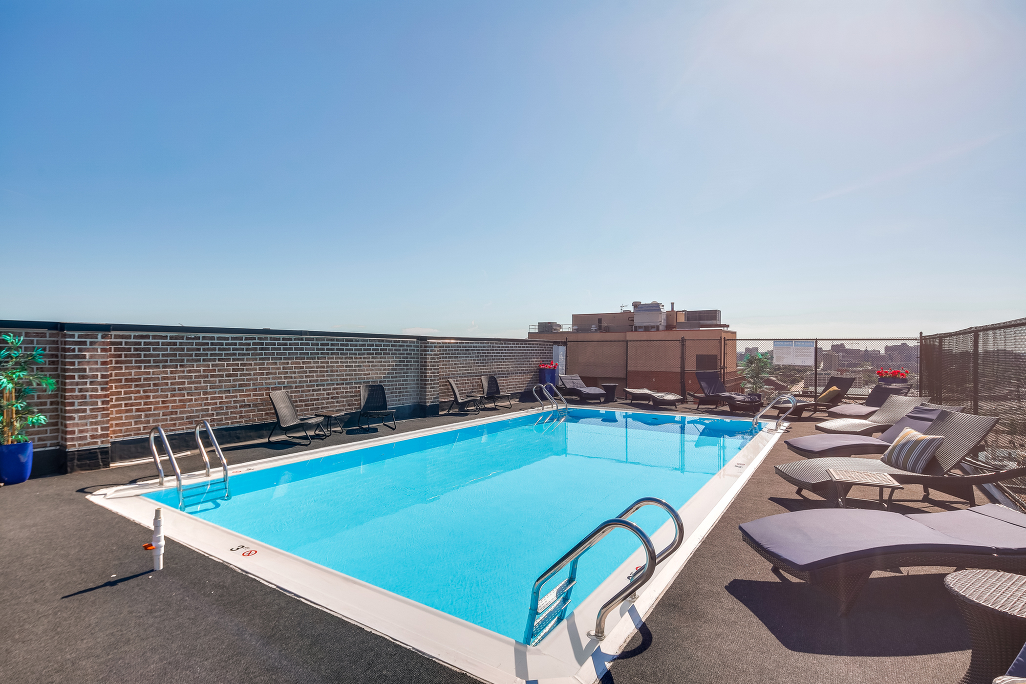 Luxurious rooftop pool with chic lounge chairs and stunning city skyline views, perfect for relaxation and sunshine.