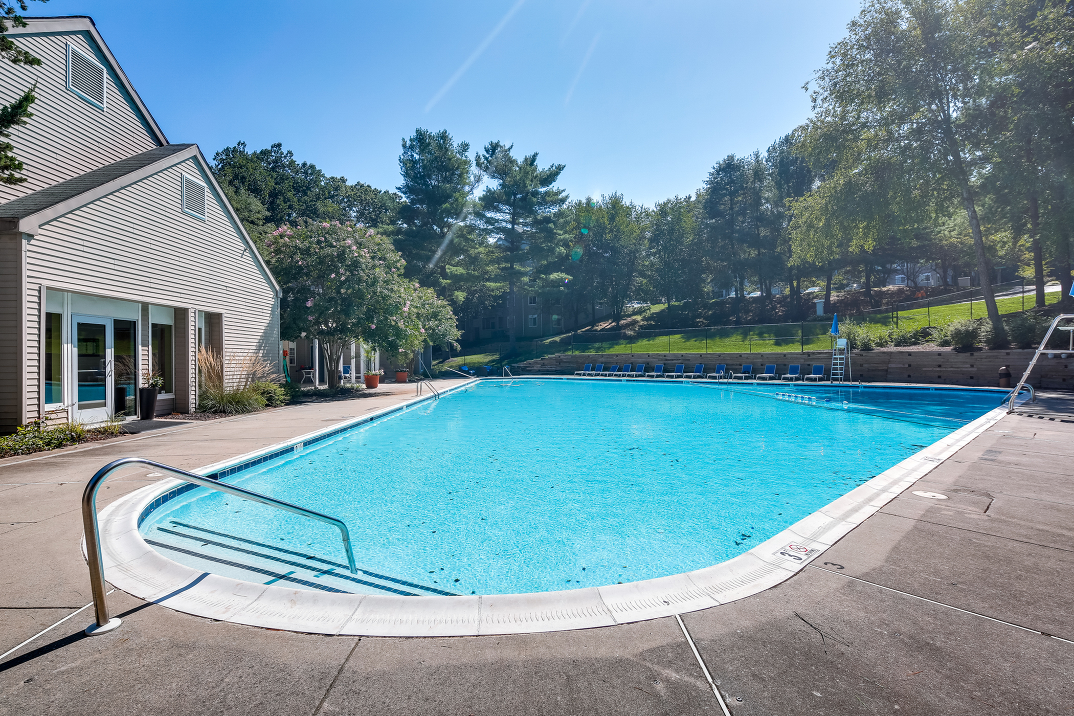 Inviting outdoor swimming pool surrounded by lush greenery and sun loungers, perfect for relaxation and recreation.