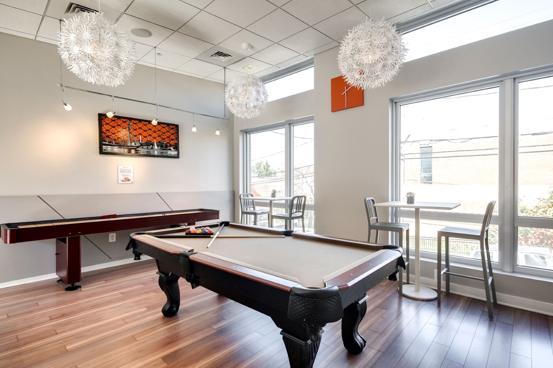 Modern leisure room with a stylish pool table, bright window seating, and contemporary lighting.