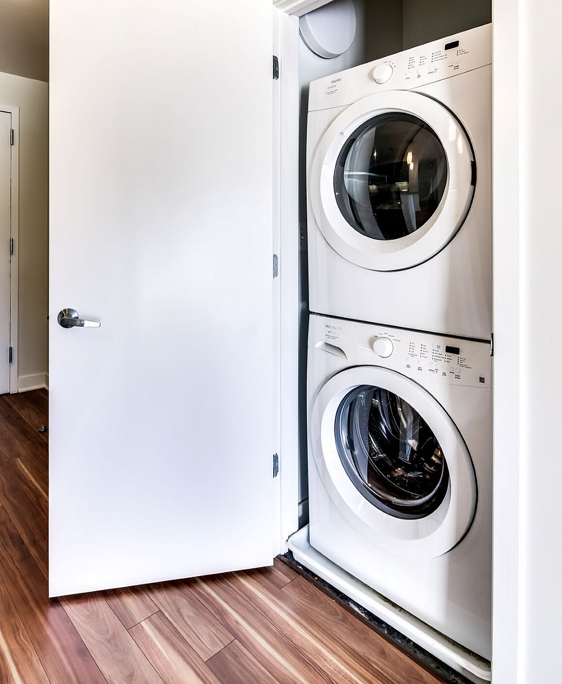 Modern apartment featuring an in-unit stacked washer and dryer with elegant wood flooring.