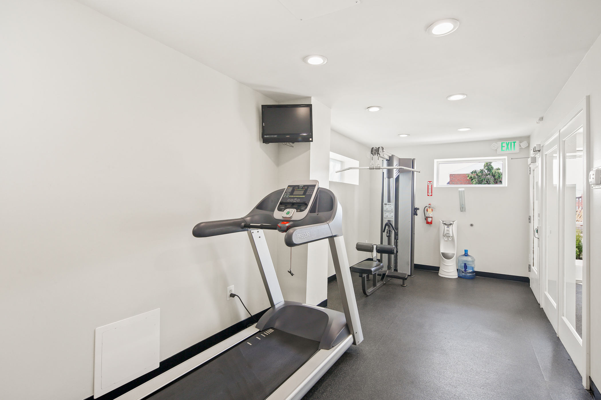 Bright and modern fitness room featuring a treadmill and multi-gym equipment, perfect for an energizing workout.