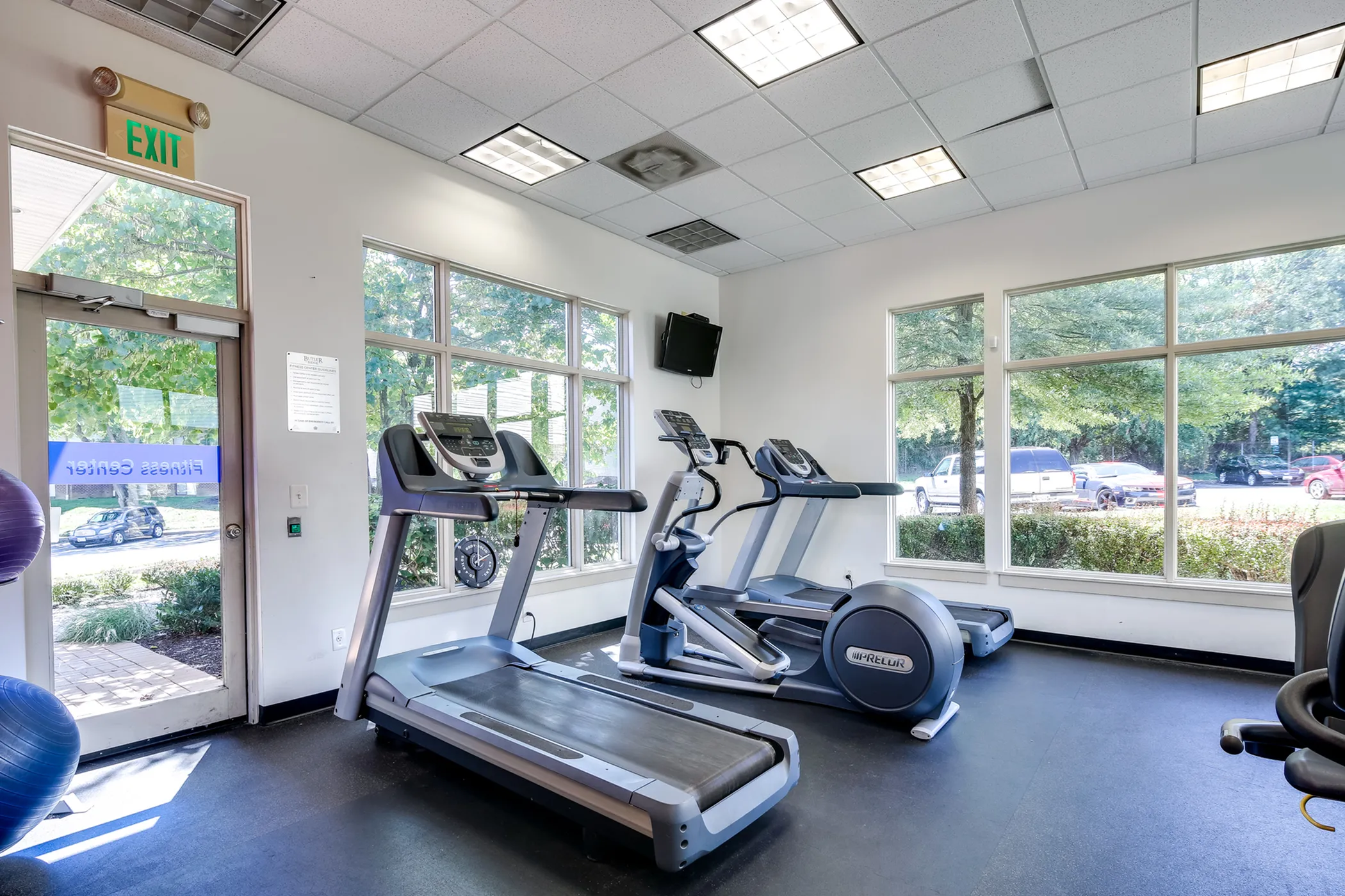 Bright fitness center with modern treadmills and large windows overlooking lush greenery.