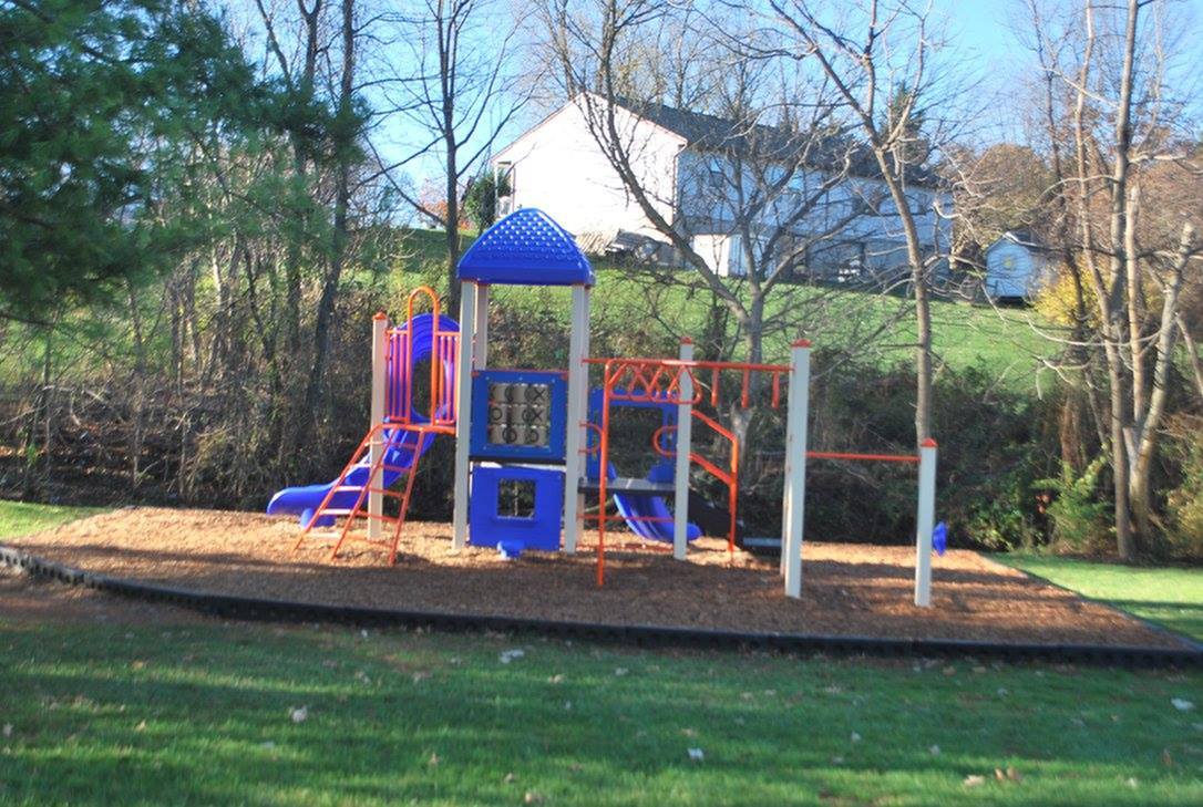Charming outdoor playground with colorful slides and climbing structures, nestled in a lush green natural setting.