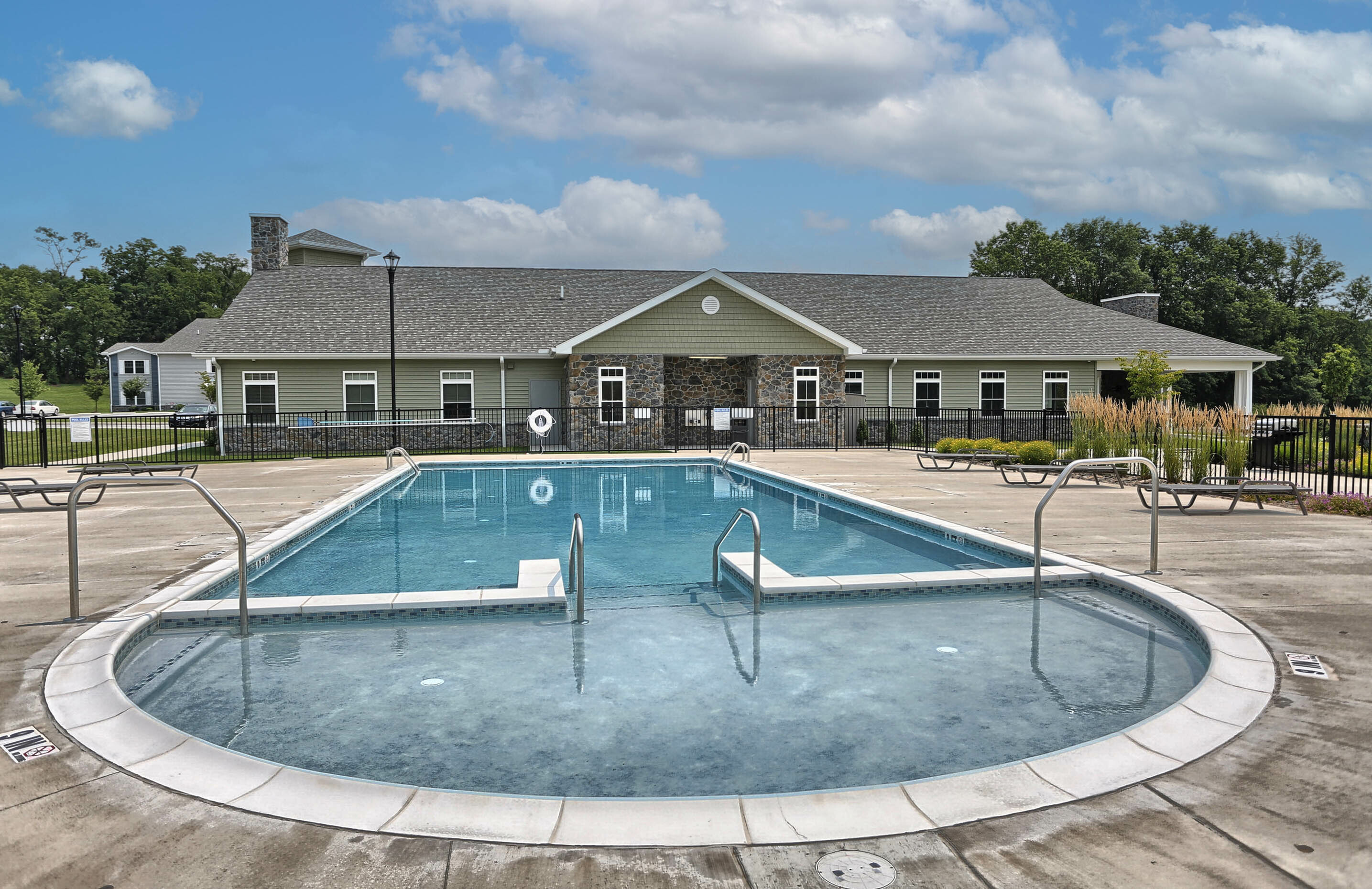 Charming community pool with crystal-clear water, surrounded by a scenic landscaped setting and a beautiful clubhouse, perfect for relaxation and enjoyment.