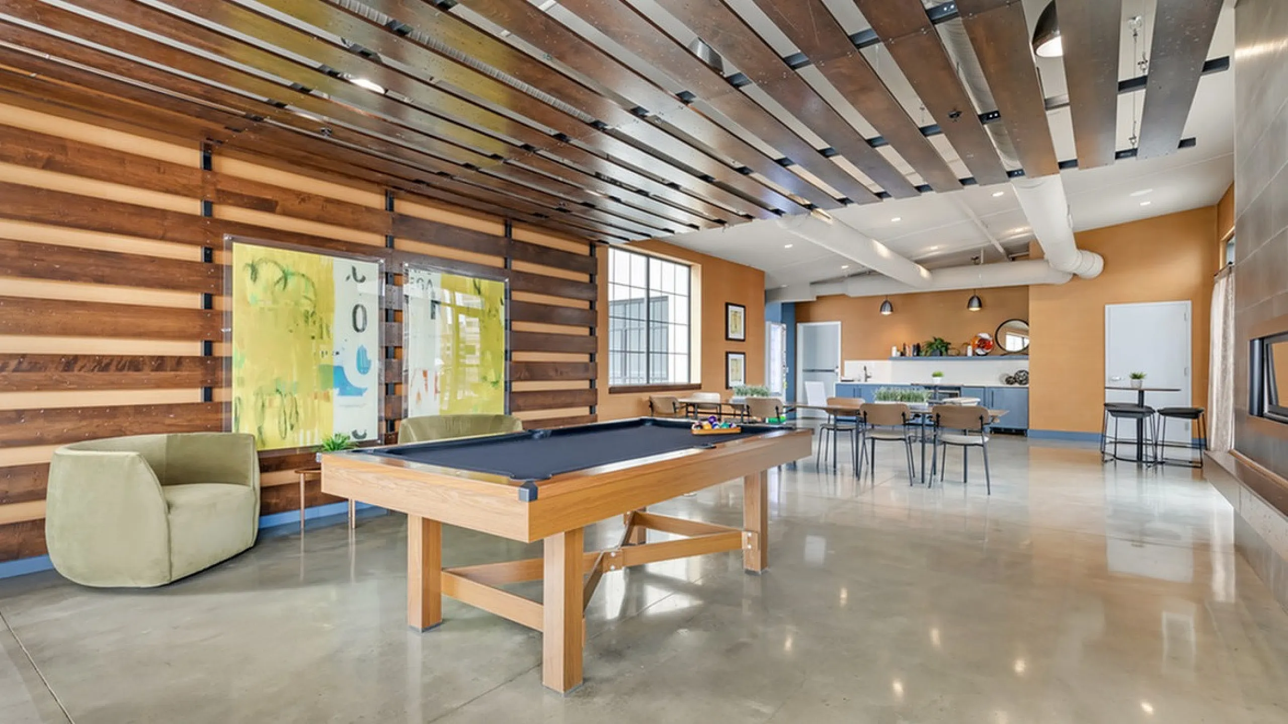 Spacious game room with a sleek pool table, stylish seating, and a contemporary design