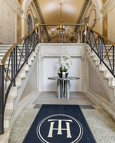 Luxurious marble staircase leading to a beautifully designed hallway in a sophisticated apartment building.