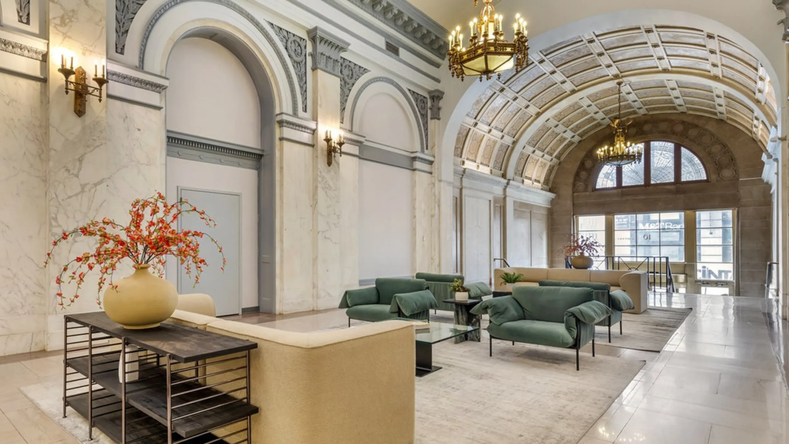 Elegant lobby with marble walls, plush teal armchairs, and ornate chandeliers