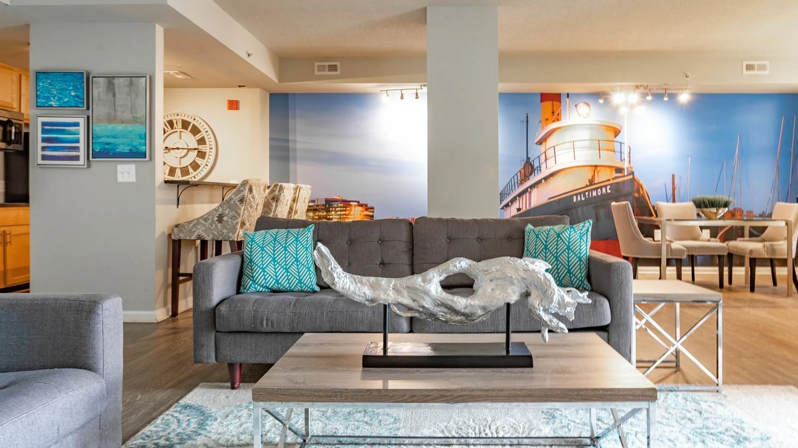 Modern living room with elegant decor, featuring a stylish gray sofa, vibrant pillows, and a unique sculpture centerpiece.
