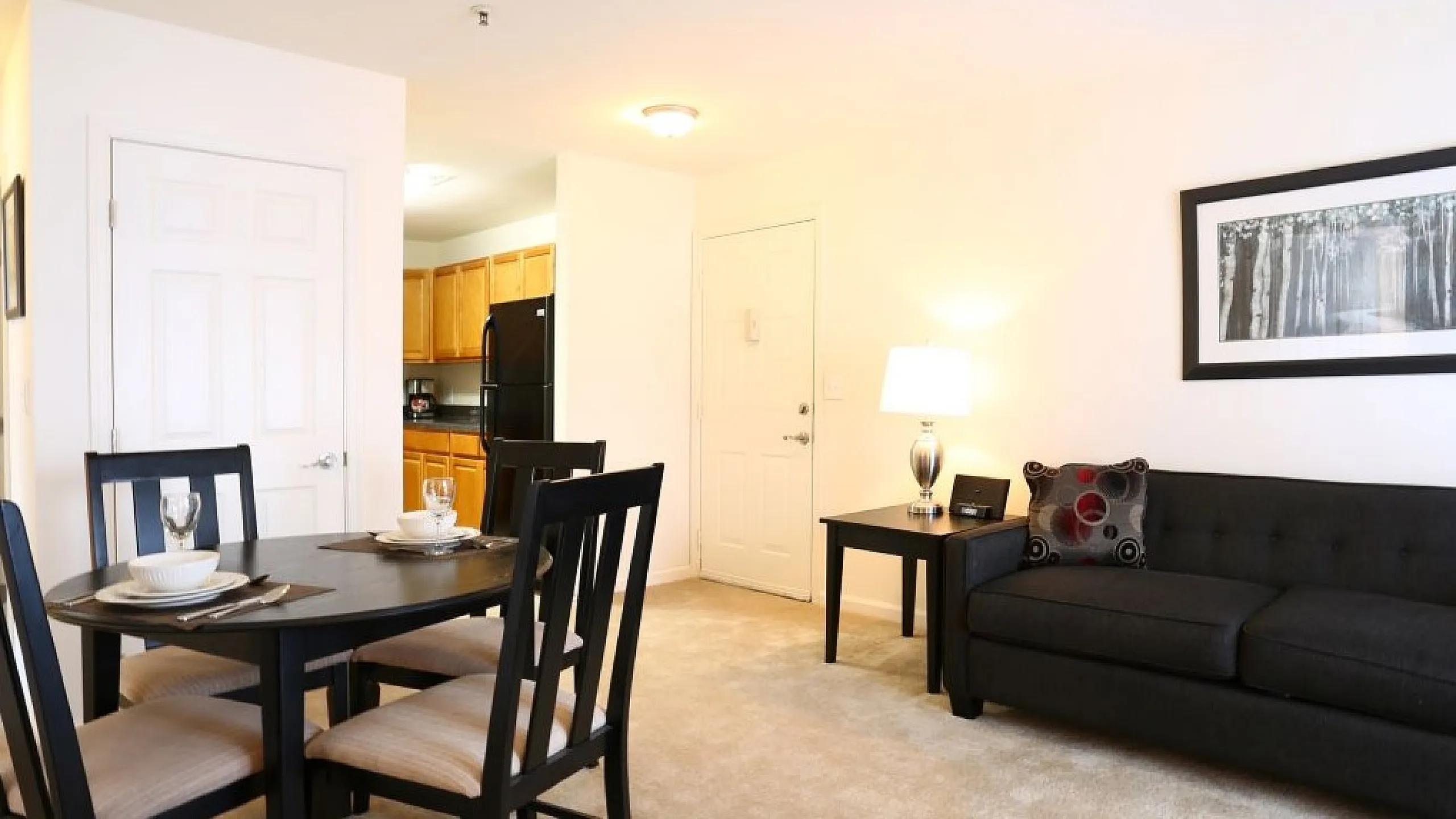Inviting living room with a modern black sofa, elegant dining area, and a well-lit open space.