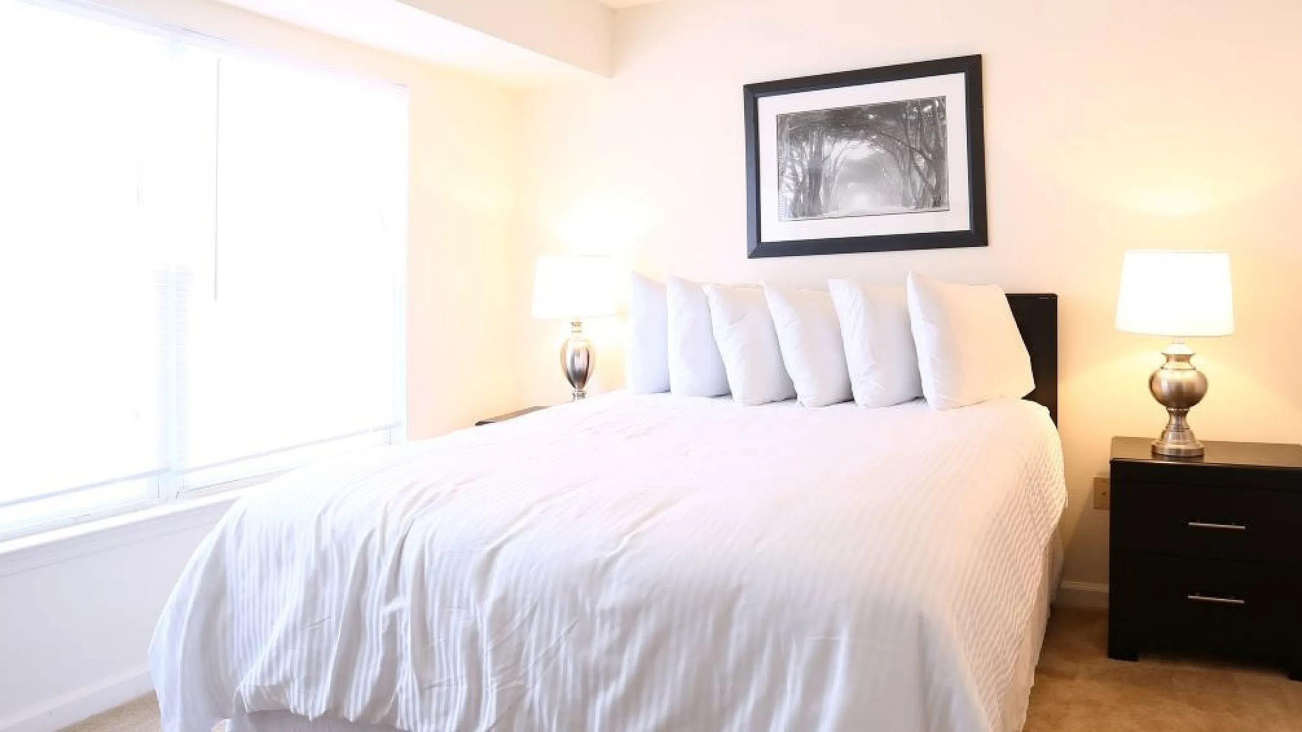 Bright and inviting bedroom with a plush white bed, elegant nightstands, and soft lighting.